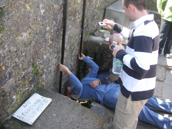 Un turista besando la piedra de la elocuencia del castillo de Blarney
