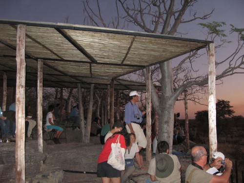 Gente en las gradas de la charca de Halali en Etosha Park durante la puesta de sol