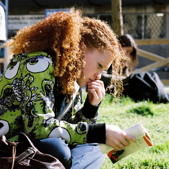 Chica concentrada leyendo un libro en la plaza de Tallers, Barcelona